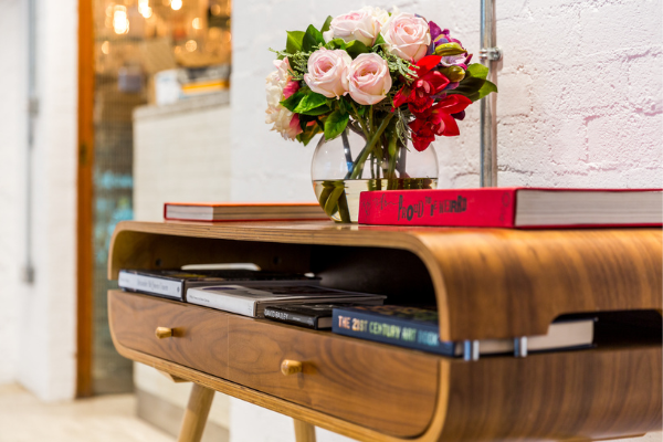 Elegant hotel lobby with chic wooden table, fresh floral arrangement, and stylish books creating a welcoming atmosphere.